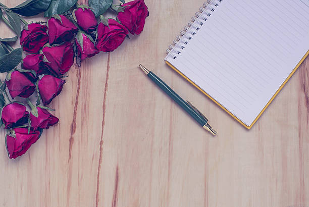 istock Notebook and pen and rose flowers on wooden background 530193148