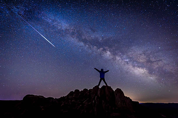 Homem com estrelas brilhantes disparo sob Via Láctea Galáxia - foto de acervo