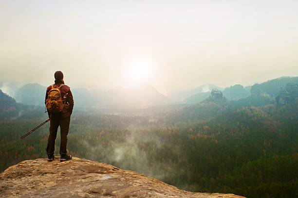 istock Tourist on cliff watching into deep misty valley bellow. 530197704