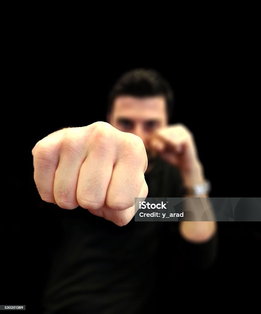 Young Man Punching with a Jab Young man throwing a punch (jab) with the fist in focus and the young man blurred with black background Adult Stock Photo
