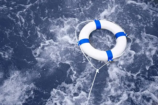 White lifebuoy, lifebelt, life saver rescue in a ocean storm full of foam
