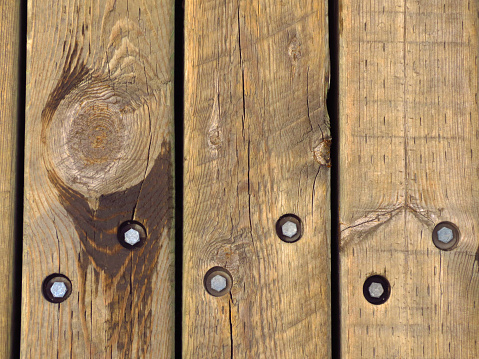 Horizontal shot of a detailed wooden fence with bolts exposed.