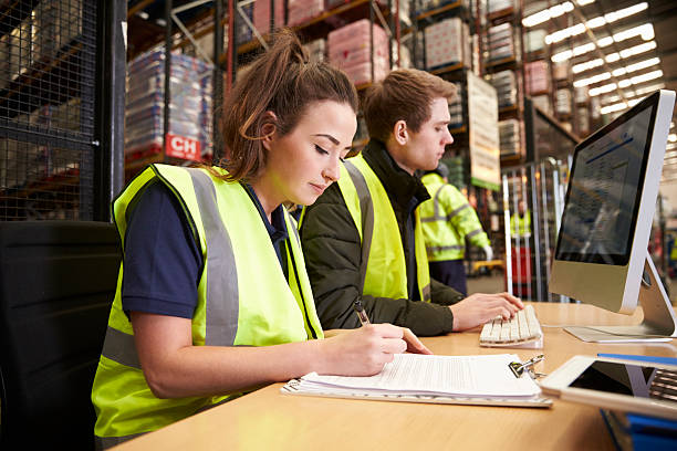 Staff managing warehouse logistics in an on-site office Staff managing warehouse logistics in an on-site office warehouse office stock pictures, royalty-free photos & images