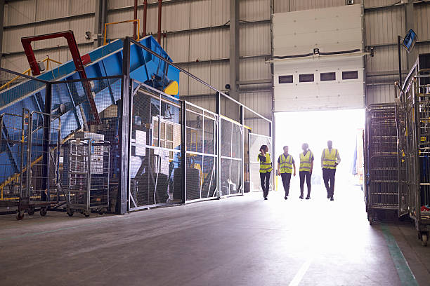 Four coworkers walking in an industrial interior, wide view Four coworkers walking in an industrial interior, wide view recycling center stock pictures, royalty-free photos & images