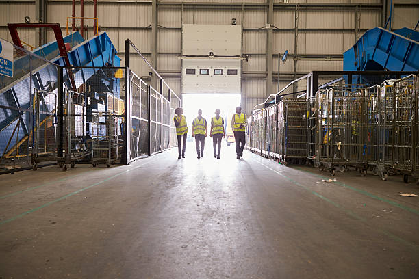 Four colleagues leaving a warehouse approach the exit Four colleagues leaving a warehouse approach the exit recycling center stock pictures, royalty-free photos & images