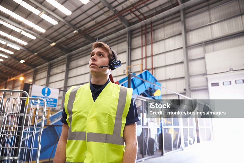 Man with reflective vest and headset standing in a warehouse Recycling Center Stock Photo