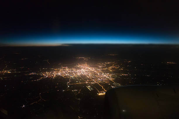 blick auf die stadt bei nacht vom fenster in ein flugzeug - city night cityscape aerial view stock-fotos und bilder