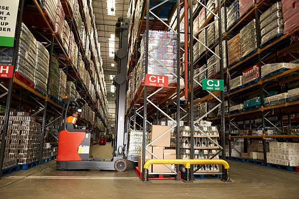 istock Man using aisle truck in a distribution warehouse, back view 530204602
