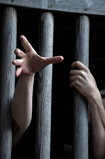 istock prisoner behind wooden bars 530205462