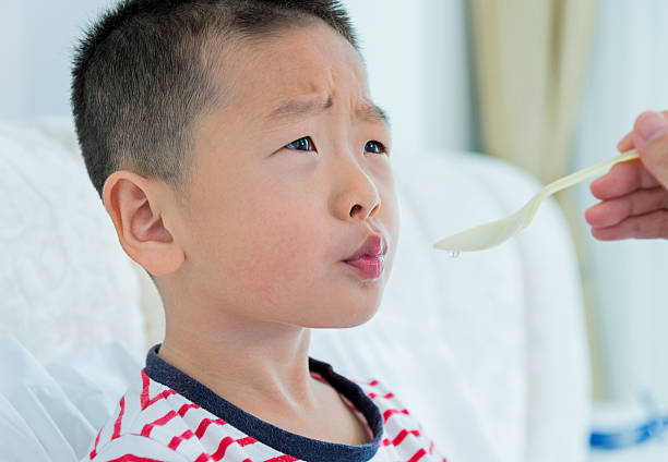 sick child having medicine Sick little boy taking medicine liquid syrup from his mother. child liquid medicine stock pictures, royalty-free photos & images