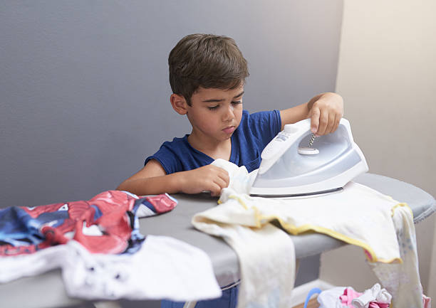Mother holding small baby while ironing, carrying him around house. Unconditional paternal love, mother's Day.