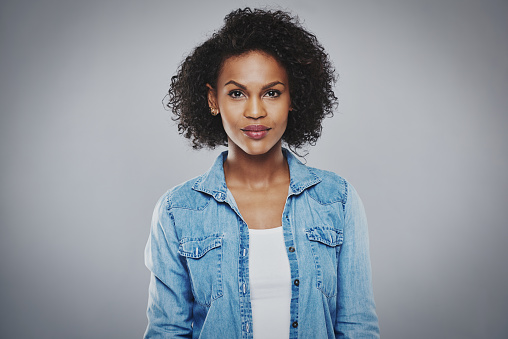 Serious beautiful black woman with blue jean shirt on gray background