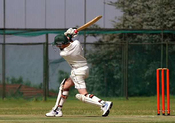 Cricket boy hitting ball A young left hand cricket player drives the ball through the covers and ends with a beautiful follow-through batsman photos stock pictures, royalty-free photos & images
