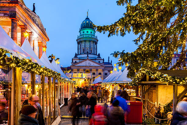 Berlin, Germany - December 2, 2013: View of people making their way through the Christmas market set up in Gendarmenmarkt in Berlin, Germany during twilight. The French Cathedral can be seen in the background.