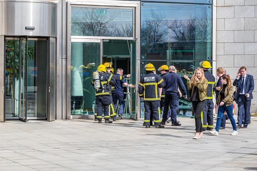 Dublin, Ireland - April 21, 2016: A group of firefighters from Dublin Fire Brigade gathered outside office building after evacuation. 