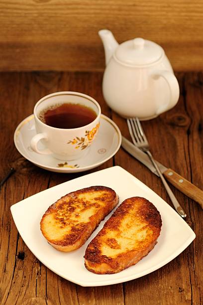 Two white toasts on white plate with cup of tea