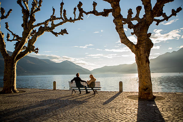 istock People relaxing on bench near lake at sunset 530250891