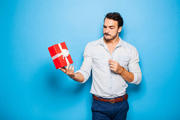 handsome adult man on blue background with christmas gift stock photo
