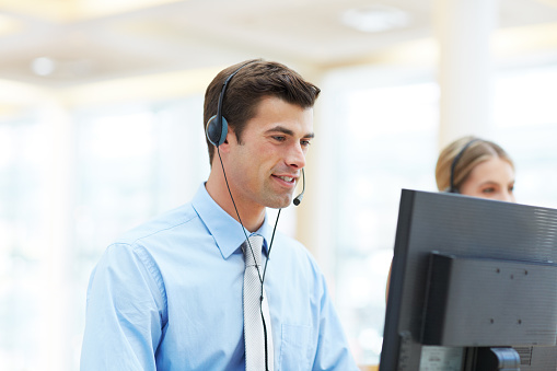 Cropped shot of a handsome young man working in a call center with colleagues in the background