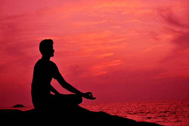 istock Silhouette of young man meditating at sunset 530271565