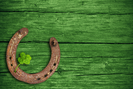 Lucky charms, horse nail and four-leaf clover with green wooden background, st patricks day.