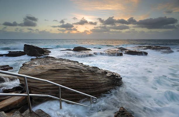 Giles Baths  at Coogee  is known as a bogey hole a semiformal rock pool open to the surging surf. In calm seas and low tide is a serene idyllic rockpool suitable for children but can also be a rough and tumble whitewater washing machine in high and  turbulent seas.  In lower tide there is a large flat rock shelf at the bottom of the stairs for visitors to lay out towels or keep belongings.  Too rough for a swim today