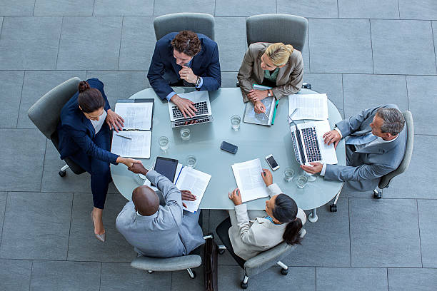 businesspeople shaking hands at conference table - board room conference table table meeting stock-fotos und bilder