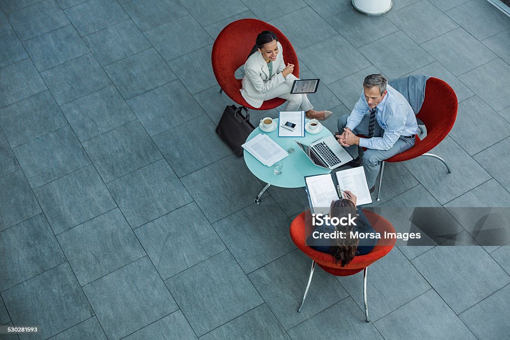 Businesspeople discussing strategy at coffee table High angle view of businesspeople discussing strategy at coffee table in office Business Meeting Stock Photo