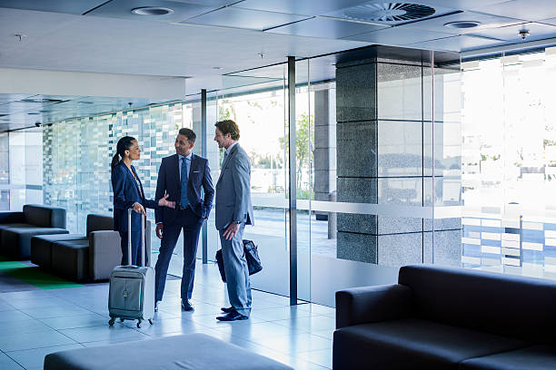 businesspeople with luggage discussing at lobby - three people group of people standing business person fotografías e imágenes de stock