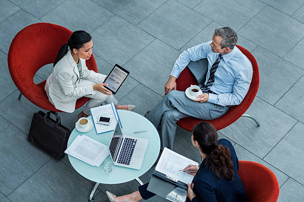 Businesspeople discussing strategy in office High angle view of businesspeople discussing strategy at coffee table in office armchair photos stock pictures, royalty-free photos & images
