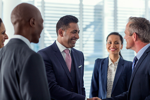 Happy multi-ethnic businesspeople shaking hands in office