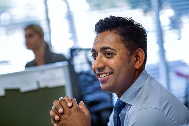 smiling businessman looking away in office - business blue business person businessman - fotografias e filmes do acervo