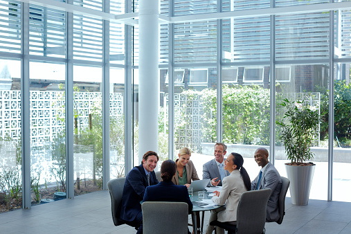 Happy multi-ethnic business professionals discussing at conference table in office