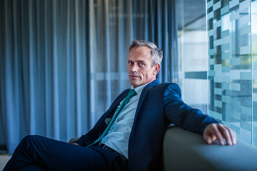 Portrait of confident businessman relaxing on sofa in office lobby