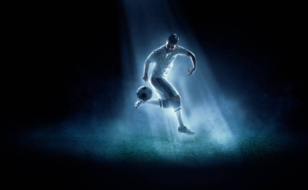 football joueur frappe de balle dans spotlight - soccer player men flying kicking photos et images de collection