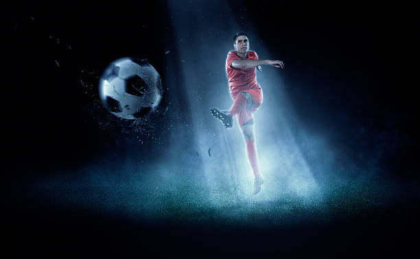 football joueur frappe de balle dans spotlight - soccer player men flying kicking photos et images de collection
