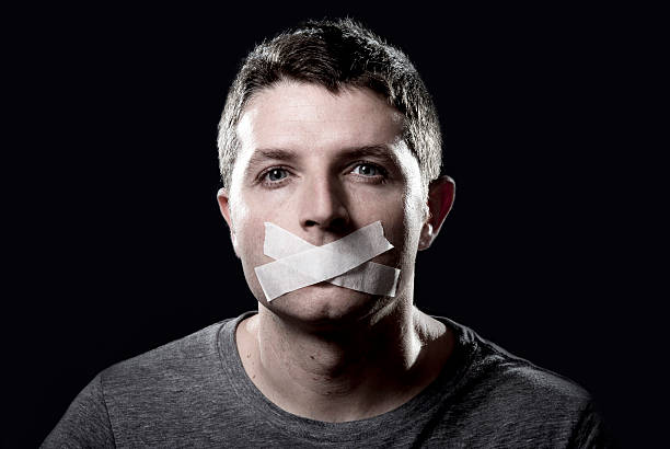 attractive young man mouth sealed on adhesive tape attractive young man with mouth and lips sealed on tape to prevent from speaking free keeping him mute and censored in freedom of speech and expression concept closed mouth stock pictures, royalty-free photos & images