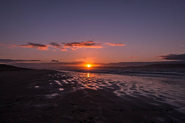 istock Footsteps in sand on beach at sunrise 530301511