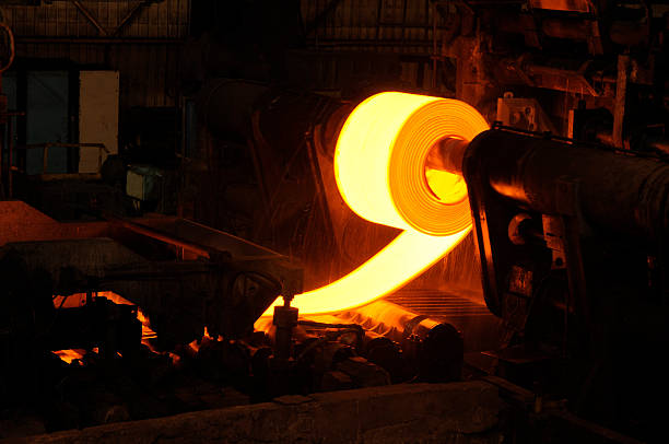 Golden Rolling Hot Steel in Steel Manufacturing Factory. Golden Rolling Coil of Hot Steel  compressed in steel sheet to be used for truck frames, automotive wheels, pipe and tubular, water heaters, agriculture equipment,  compressor shells, rail car components, wheel rims, metal buildings, railroad-hopper cars, doors, shelving, discs, guard rails, automotive clutch plates. steel mill stock pictures, royalty-free photos & images