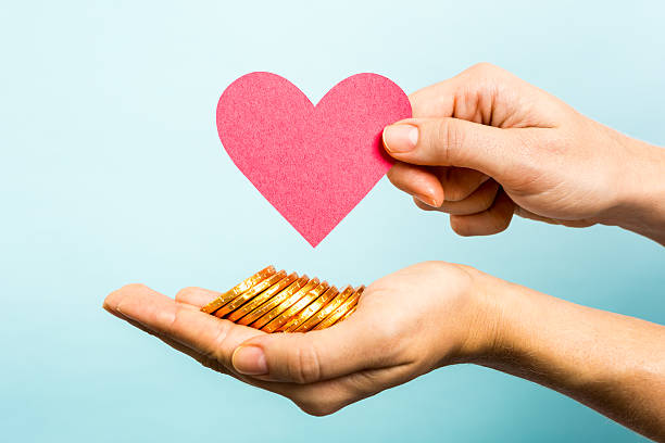 monedas de oro, de papel rojo corazón forma.  amor y dinero concepto - micromecenazgo fotografías e imágenes de stock