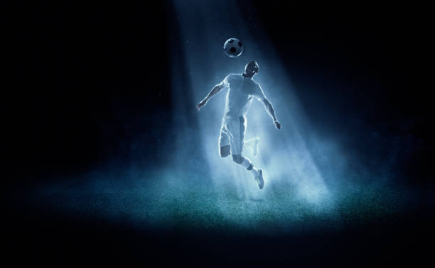 football joueur frappe de balle dans spotlight - soccer player men flying kicking photos et images de collection