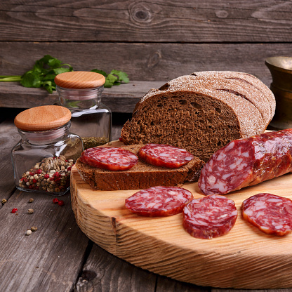 Sliced salami and bread on a cutting board, square photo