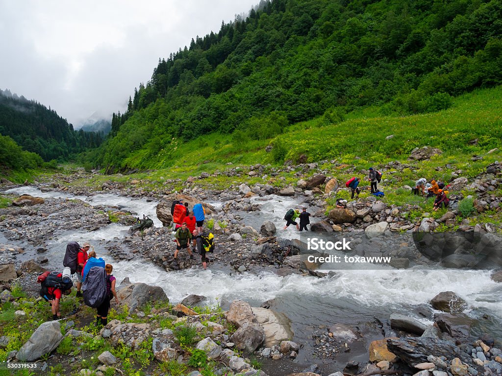 Hikers group cross the mountain river Hikers cross the mountain river ford Activity Stock Photo