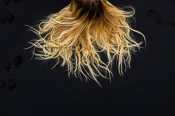 spesso capelli bionda in contrasto sulla sabbia nera - surfy foto e immagini stock