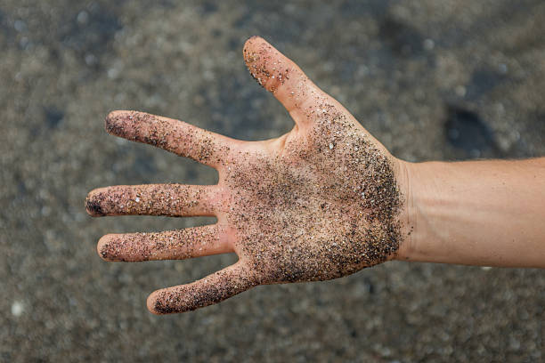 istock Hand covered in big grains of black sand 530323143