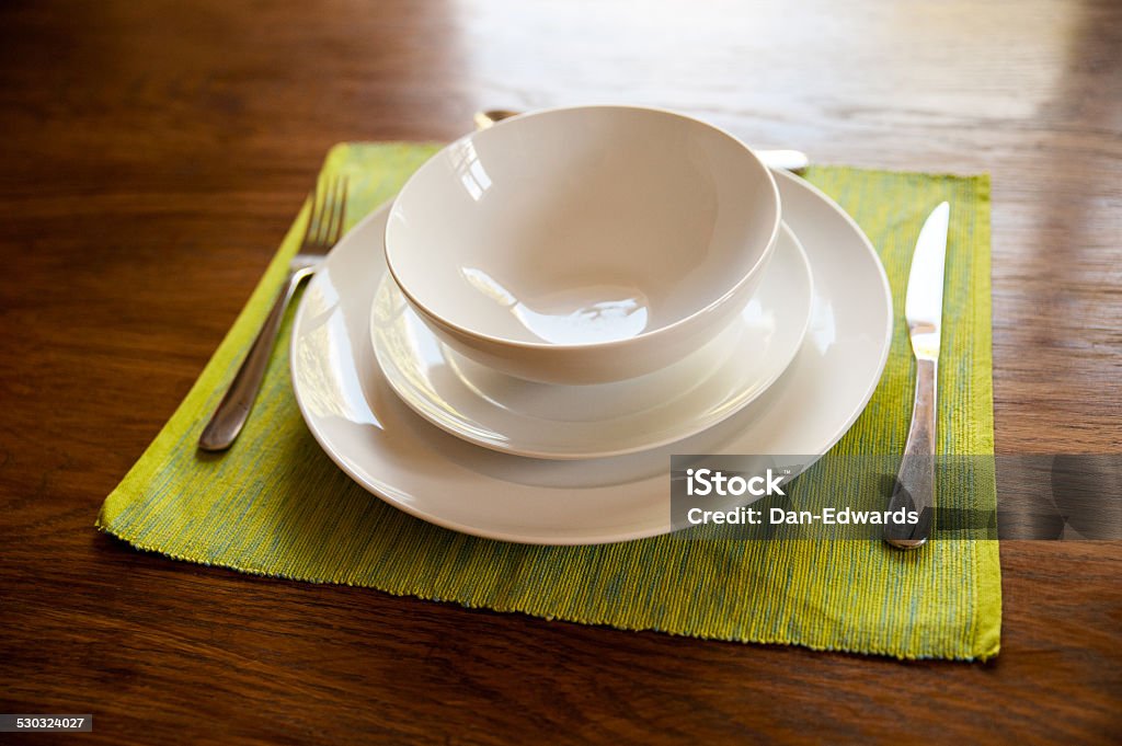Dinner service White dinner service on a green place mat and with an oak wood table background Backgrounds Stock Photo