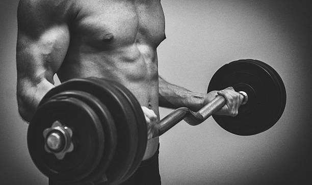 istock Muscular male model doing exercises with barbell. Black and white. 530335073