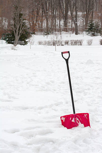 istock Red plastic shovel with black handle stuck in fluffy snow. 530336043