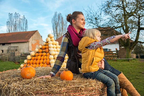 istock Mother and child sitting on haystack with pumpkins 530348953