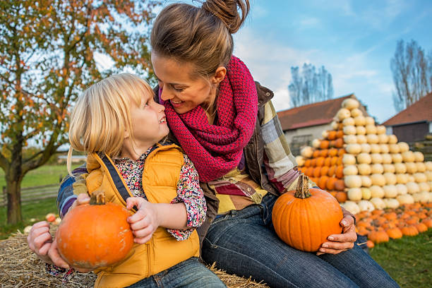 istock smiling mother and child sitting on haystack with pumpkins 530348959